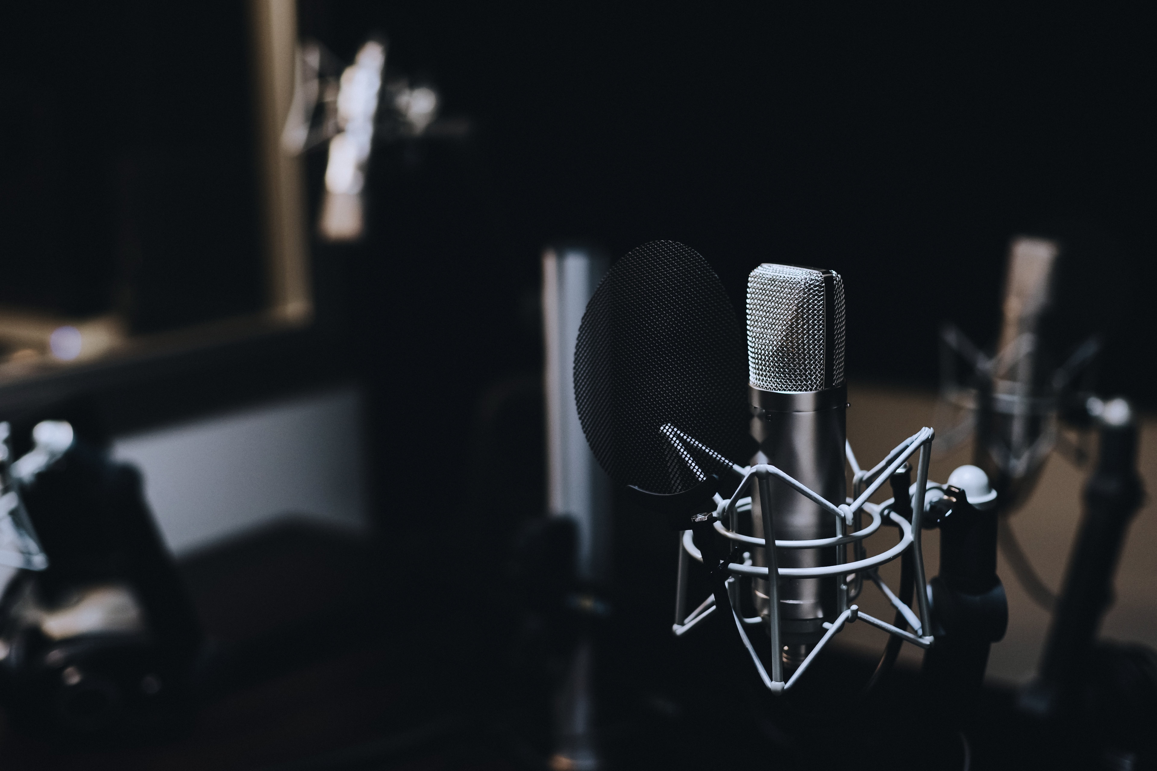 A condenser microphone with pop filter in a dark studio