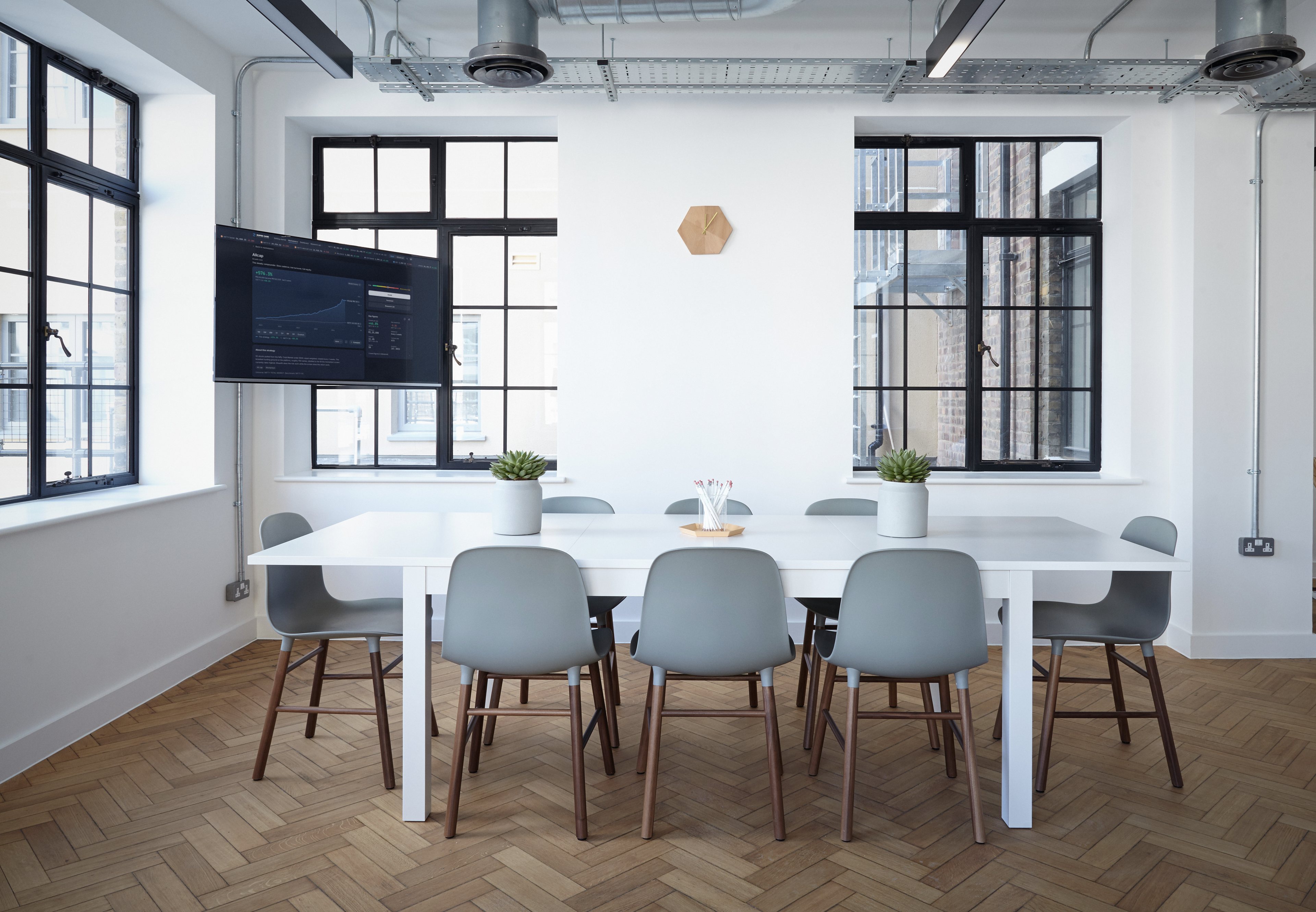 A bright family office meeting room with the RupeeCase Allcap strategy on the wall screen