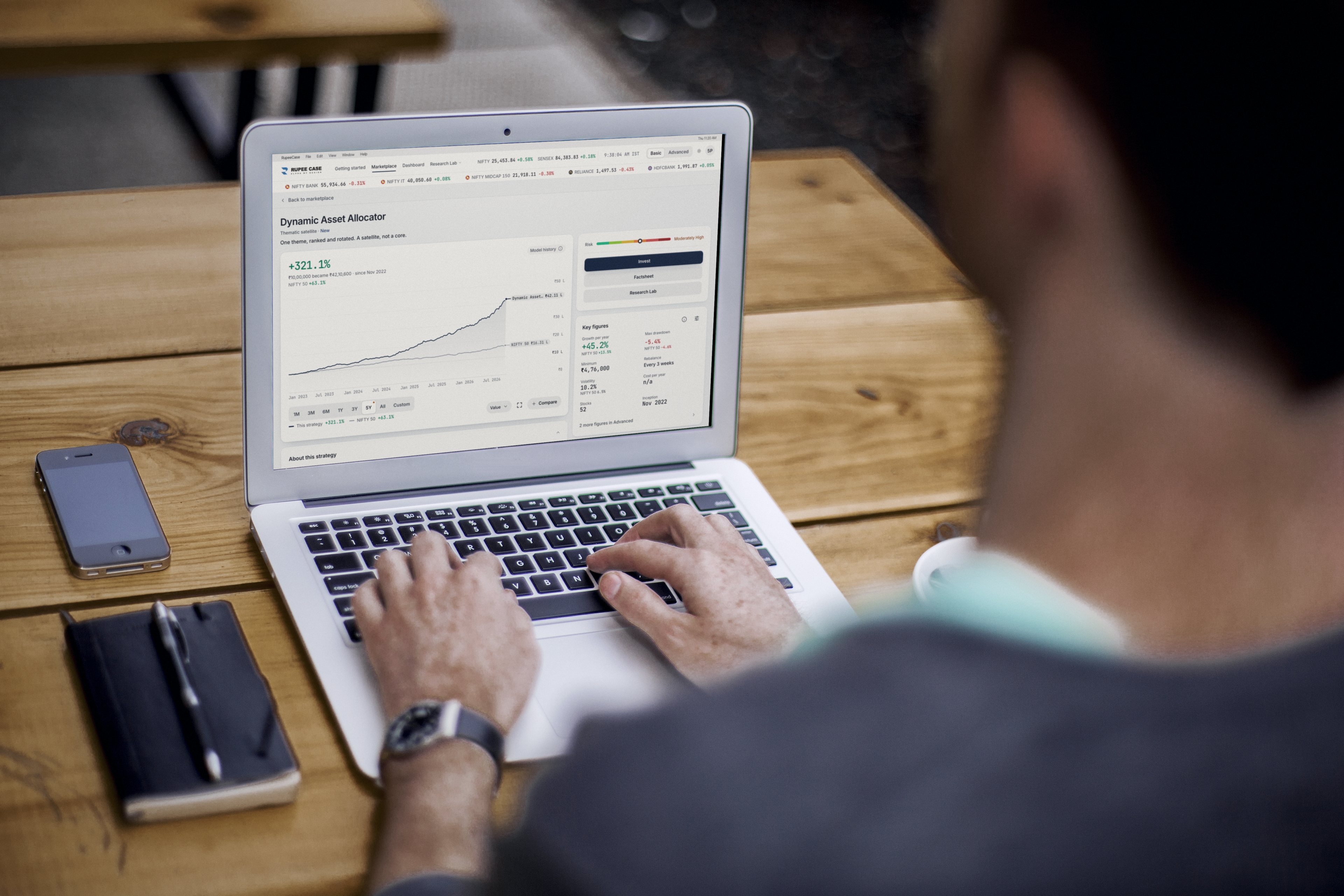 Over the shoulder view of a person typing on a laptop showing the RupeeCase Dynamic Asset Allocator strategy page