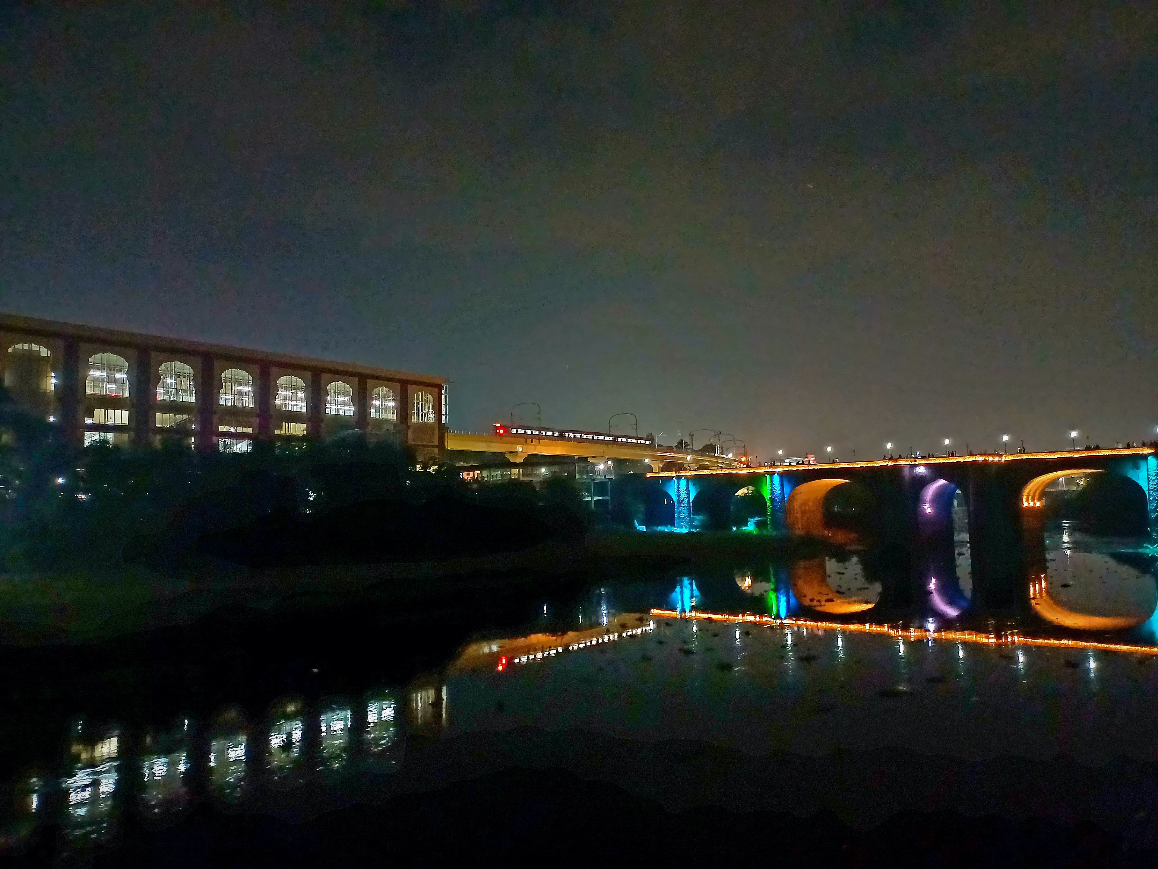 Pune metro viaduct and the lit Shivaji Bridge reflected in the Mutha river at night
